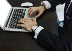 Cropped image of a young man working on his laptop , rear view of business man hands busy using laptop at office desk, young male student typing on computer sitting at wooden table